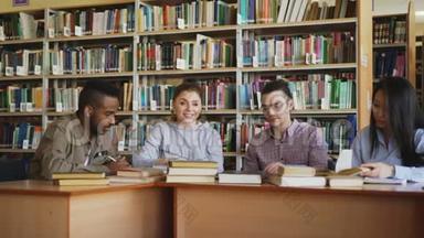 多民族学生在大学图书馆的桌旁聊天准备考试